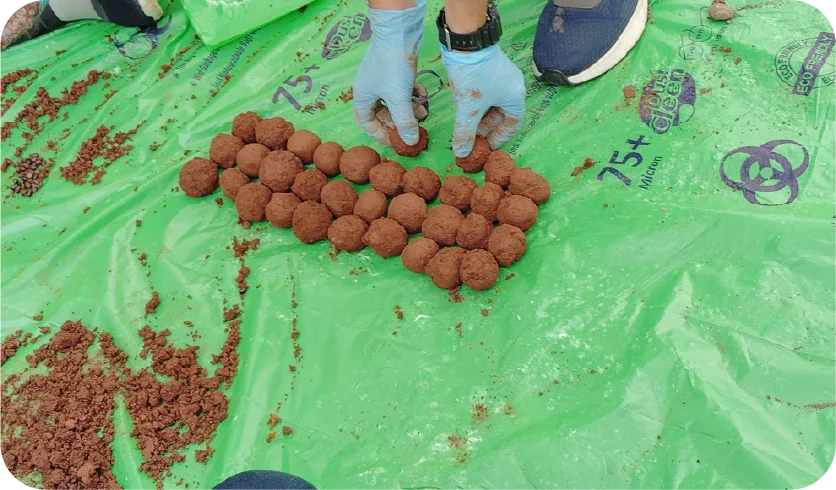 Group of volunteers participating in a seedball preparation activity outdoors